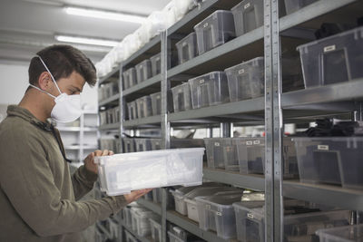 Side view of man carrying container while standing indoors