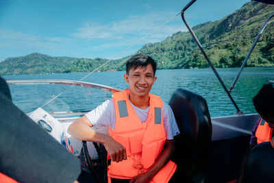 Portrait of smiling young man in sea against sky