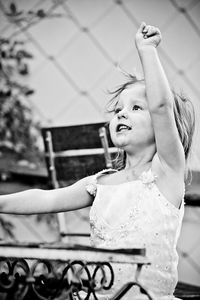 Close-up of excited girl with arm raised while sitting on chair