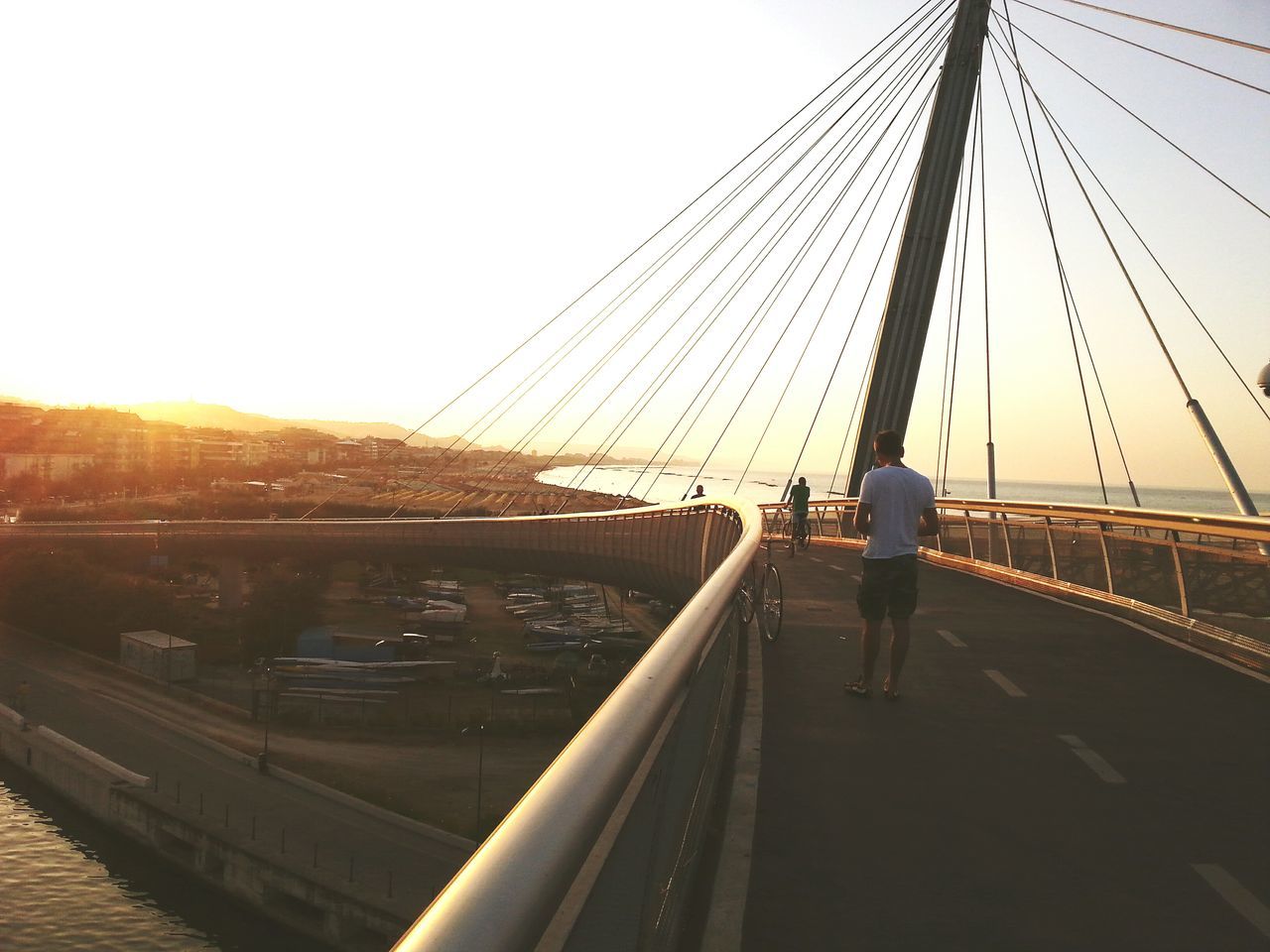 sunset, sky, full length, bridge - man made structure, leisure activity, connection, one person, outdoors, built structure, men, suspension bridge, people, day, young adult, only men, adult, adults only, architecture, one man only