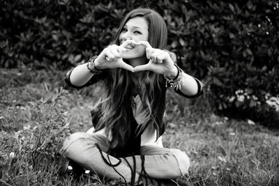 Portrait of happy young woman sitting on grass