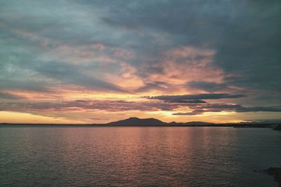 Scenic view of sea against cloudy sky at sunset