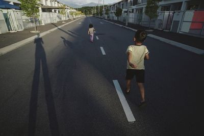 Rear view of people on road with city in background