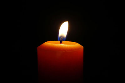 Close-up of lit candle against black background