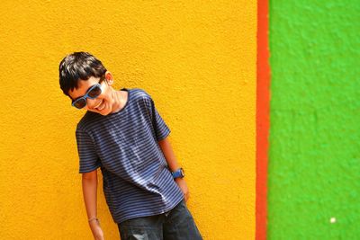 Happy boy laughing against yellow wall