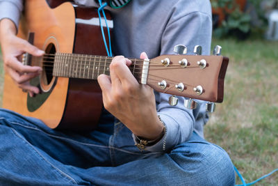 Midsection of man playing guitar outdoors