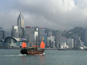 Boats in sea against cloudy sky