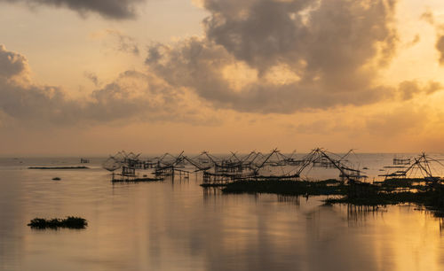 Silhouette of marina against cloudy sky during sunset