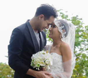 Man and woman holding flower against white background