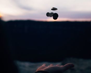 Cropped image of man flipping coins outdoors