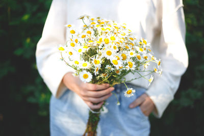 Midsection of woman holding white flower