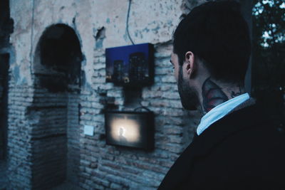 Close-up of young man against illuminated wall