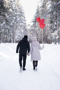 Rear view of woman walking on snow covered field