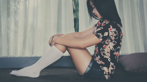 Side view of young woman sitting at home