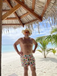 Full length of shirtless man standing at beach