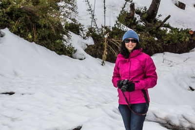 Full length portrait of woman standing on snow covered trees