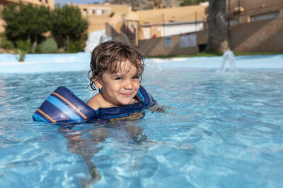 Toddler plays in the pool with children's floats. summer arrives in the northern hemisphere.