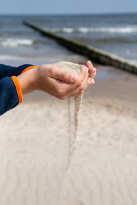 Midsection of person hand on sand at beach