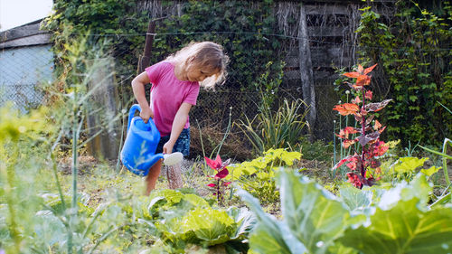 Girl watering plants in yard