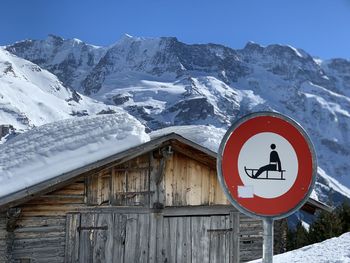 Information sign on snowcapped mountain against sky