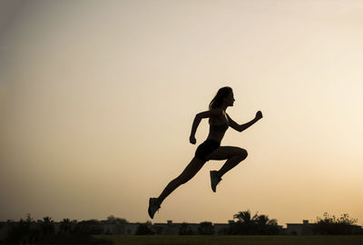 Side view of silhouette man jumping against clear sky