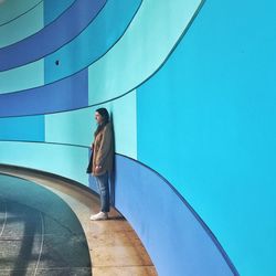 Young woman standing by wall at subway