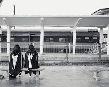 Rear view of people sitting on bridge