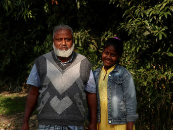 Portrait of  man and young girl standing against plants