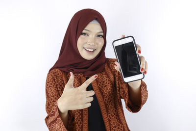Portrait of smiling young woman using smart phone against white background