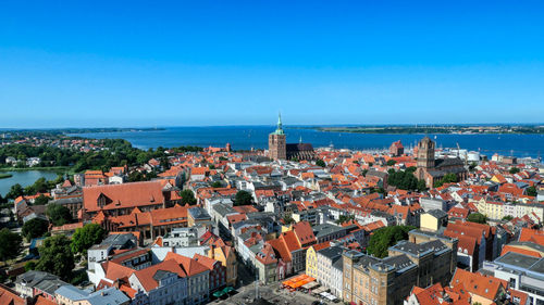 High angle view of townscape by sea against blue sky