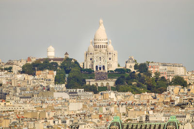 View of the sacre coeur cathedral from a distance, with hundreds of tourists on its steps.