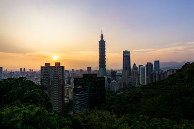 Buildings in city against sky during sunset