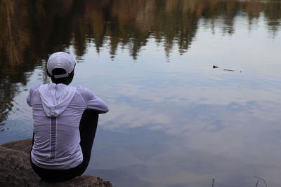 Rear view of woman sitting by lake