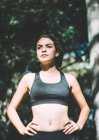 Portrait of beautiful young woman standing against trees