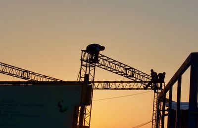 Low angle view of silhouette crane against sky during sunset