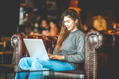 Young woman using mobile phone while sitting on chair