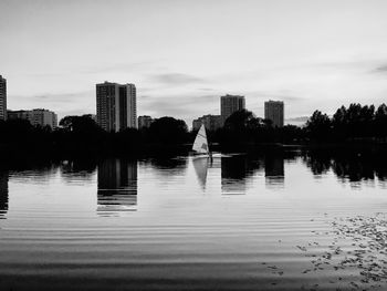 Reflection of buildings in lake against sky in city