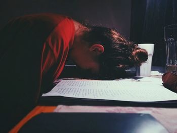 Side view of young woman leaning head on desk at home