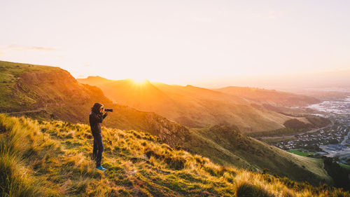 Man standing on mountain against sky during sunset