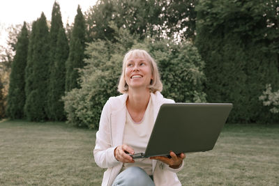 Smiling woman with laptop in park
