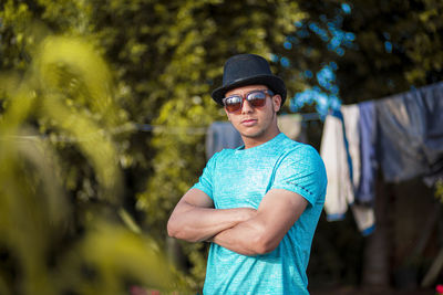 Portrait of young man wearing sunglasses standing against plants