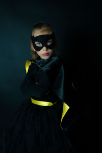 Portrait of girl wearing costume standing against black background