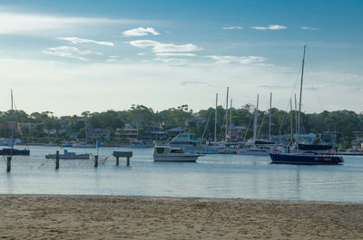 Boats moored at harbor against sky