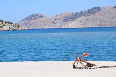 Young woman on beach against clear sky