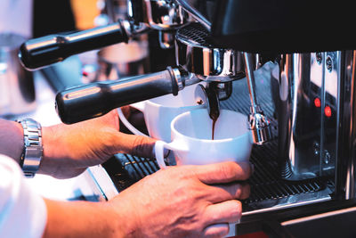 Cropped image of man holding coffee cup at cafe