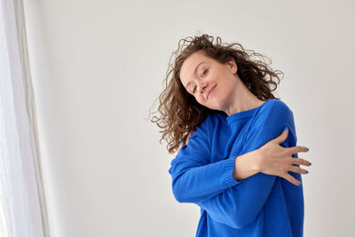 Portrait of smiling woman standing against wall