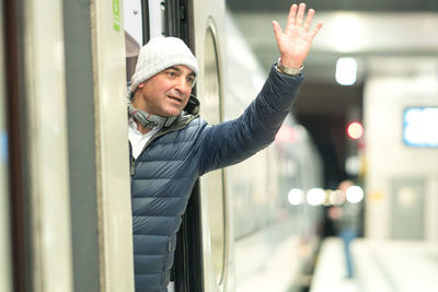 Man waving hand while standing in train