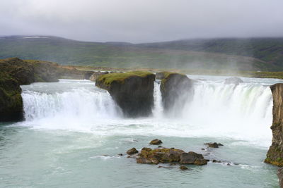 Scenic view of waterfall against sky