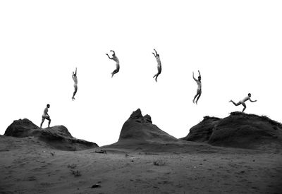 Full length of naked men jumping against field