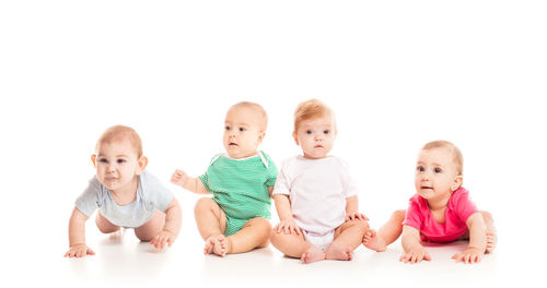 Portrait of siblings sitting against white background